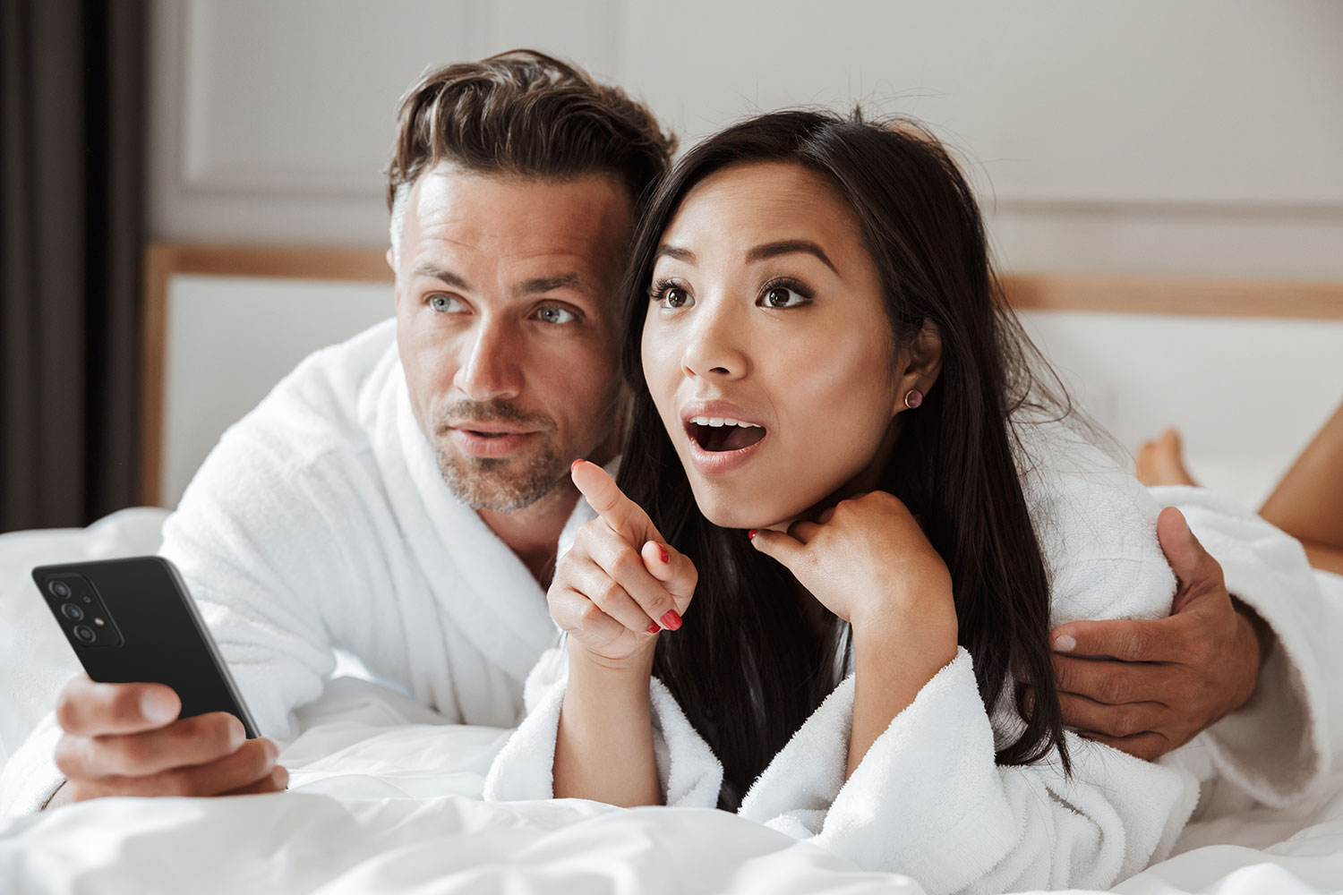 couple of hotel guests, earing robes and controlling TV with thier mobile