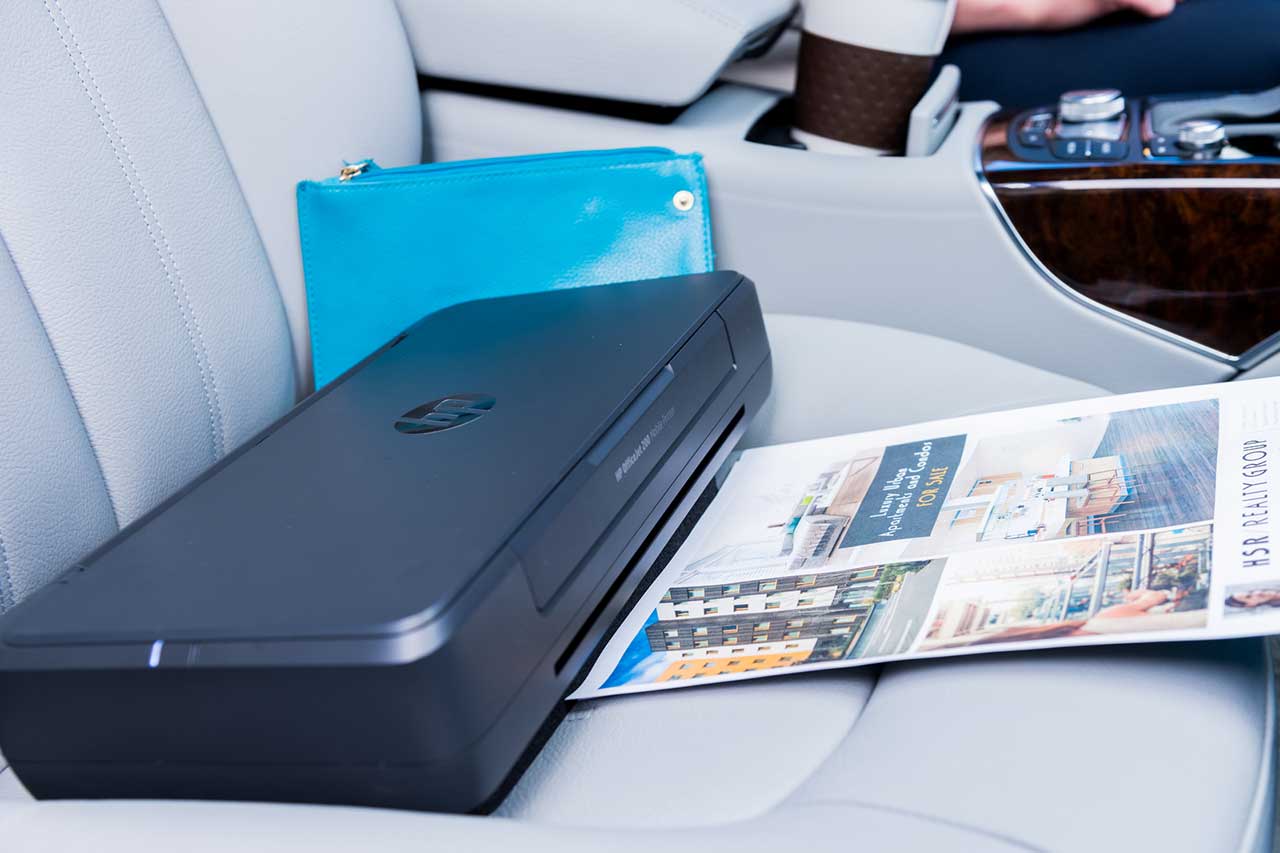 HP OfficeJet 200 portable printer in use on a car seat